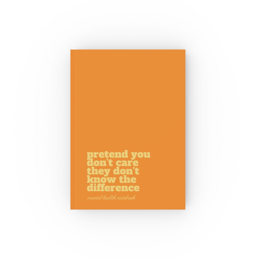 An deep orange hardcover notebook cover with bold black text reading "pretend you don't care they don't know the difference." Below, smaller text says "mental health notebook." The tone is empowering by iziiexpressions.com