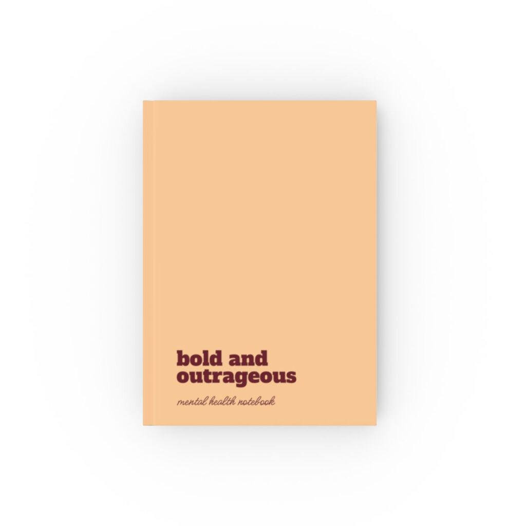 An peach hardcover notebook cover with bold maroon text reading "bold and outrageous." Below, smaller text says "mental health notebook." The tone is empowering by iziiexpressions.com