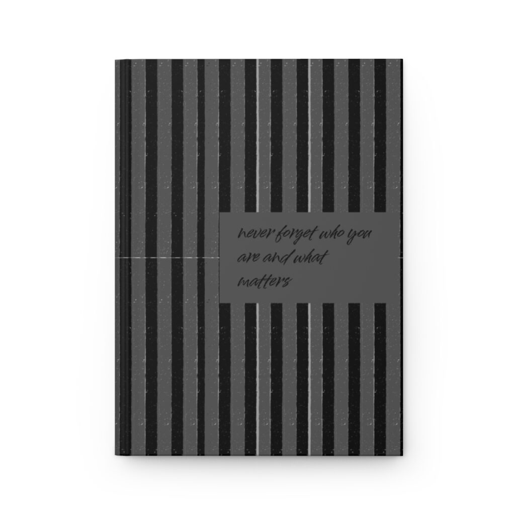 A notebook cover with vertical black and gray stripes. In the center, a gray box reads, "never forget who you are and what matters," in cursive. by iziiexpressions.com