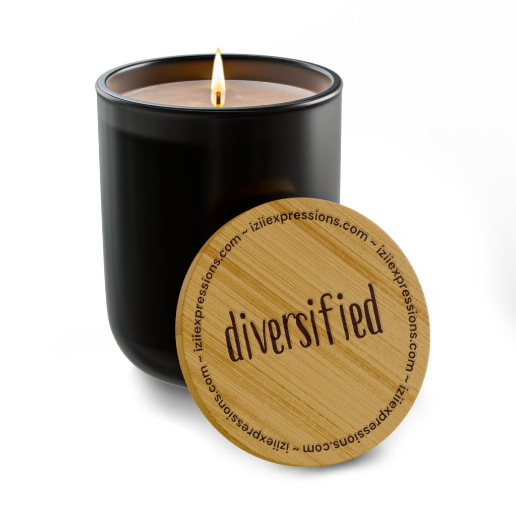 Black glass candle with a lit wick next to a wooden lid engraved with "diversified".