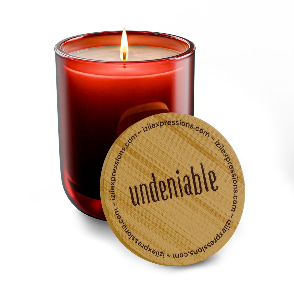 A lit red glass candle with a wooden lid labeled "undeniable" sits on a white background.